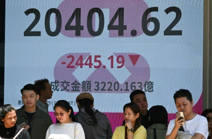 Des personnes se tiennent devant un écran de l'indice boursier Heng Seng de la Bourse de Hong Kong le 7 avril 2025