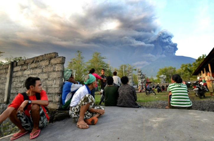 Des Balinais regardent l'épaisse fumée s'échapper du volcan du Mont Agung, le 26 novembre 2017 à Karangsem, sur l'île indonésienne de Bali