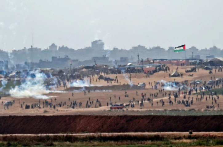 Photo prise le 15 mai 2018 depuis Israël de manifestants palestiniens essuyant des tirs de gaz lacrymogènes à Gaza, aux abords de la frontière