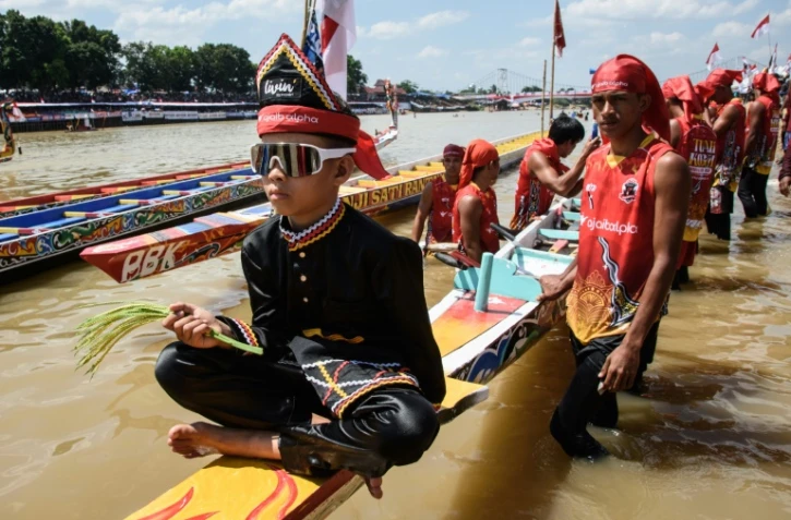 Rayyan Arkan Dikha assis à l'avant d'un bateau avant une course nautique traditionnelle, le 22 août 2025 sur la rivière Kuantan, dans la province indonésienne de Riau, sur l'île de Sumatra 