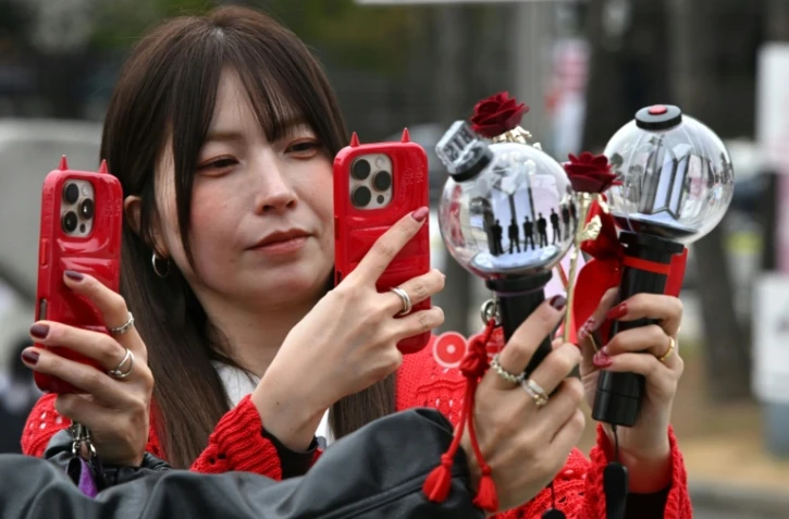 Des fans prennent des photos de bâtons lumineux à l'effigie de BTS à leur arrivée au stade où le groupe de K-pop se produira, à Goyang, le 9 avril 2026