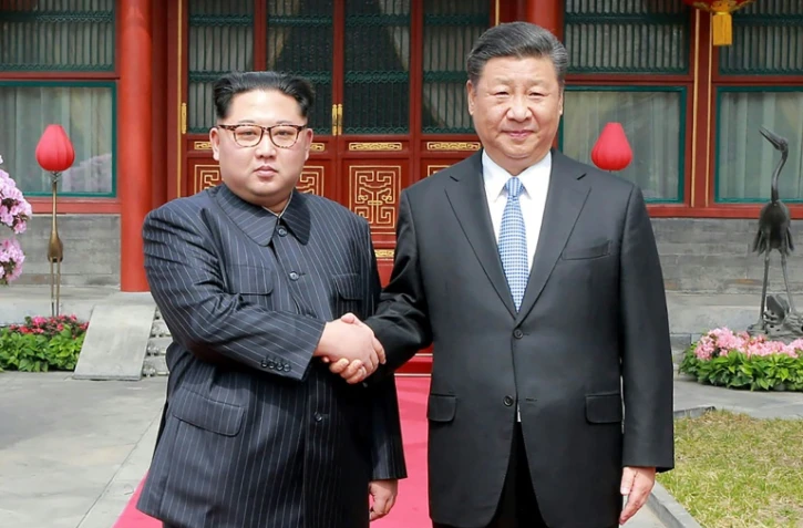 Photo fournie le 27 mars 2018 par l'agence nord-coréenne Kcna du leader nord-coréen Kim Jong-Un (g) et du président chinois Xi Jinping à Pékin