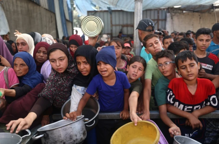 Des enfants palestiniens se rassemblent pour recevoir des portions alimentaires distribuées par une cuisine caritative à Nousseirat, dans le centre de la bande de Gaza, le 30 septembre 2025 