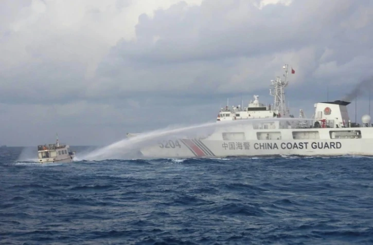 Photo diffusée, le 10 décembre 2023, par les garde-côtes philippins d'un navire des garde-côtes chinois (d) tirant au canon à eau contre un bateau de ravitaillement philippin en mer de Chine méridionale disputée