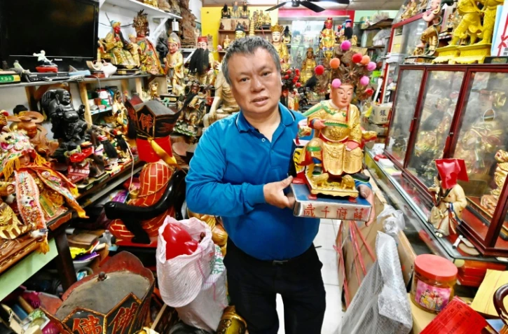 Le sculpteur Lin Hsin-lai tient la statue d'un dieu taoiste dans son atelier de Taoyuan, dans le nord de Taïwan, le 17 mars 2020