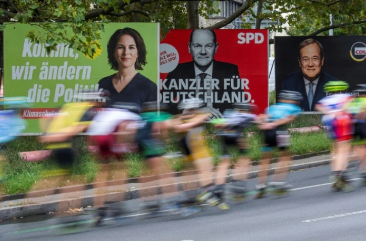 Des skaters passent devant des panneaux électoraux des trois principaux candidats à la succession de la chancelière allemande Angela Merkel, le 25 septembre 2021 à Berlin