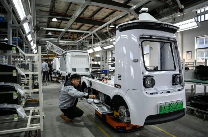 Des ouvriers travaillent sur une ligne de production de l'usine Neolix qui fabrique de petits véhicules utilitaires autonomes pour le transport de colis en ville, le 4 décembre 2025 à Yancheng dans la province chinoise du Jiangsu