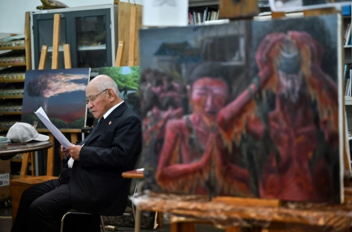 Masaki Hironaka, un survivant de la bombe atomique, assis parmi des peintures réalisées par des élèves pour préserver les témoignages des survivants, le 29 mai 2025 à Hiroshima 