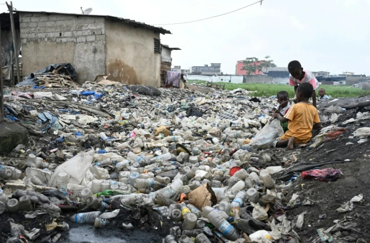 Des enfants jouent au milieu de déchets en plastique à Anyama, près d'Abidjan, le 25 mai 2023