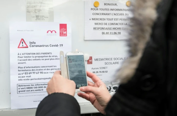 Une femme regarde un panneau d'information sur le coronavirus à Mulhouse à l'entrée d'une école, le 6 mars 2020