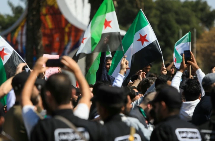 Forces de sécurité et manifestants syriens à Damas, le 15 mars 2025, pour le 14e anniversaire du soulèvement populaire de 2011