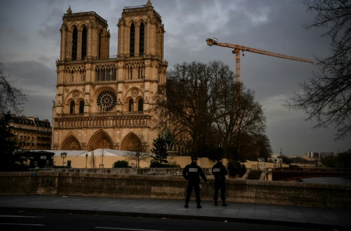 Des policiers patrouillent aux abords désertés de la cathédrale Notre-Dame de Paris, habituellement peuplés de touristes, le 17 mars 2020