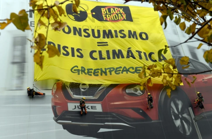 Des militants de Greenpeace ont déployé sur la façade d'un immeuble le 29 novembre 2019 à Madrid une énorme banderole : "Consumérisme=Crise climatique"