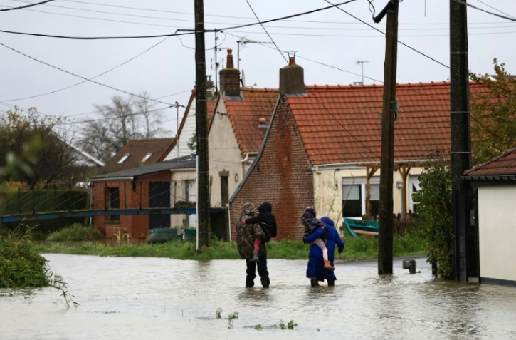 Des personnes marchent dans une rue inondée au Doulac, près de Saint-Omer, le 14 novembre 2023, dans le Pas-de-Calais