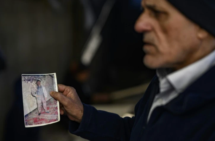 Le Turc Mehmet Erturk, tout juste libéré d'une prison syrienne, montre des photos lors d'un entretien avec l'AFP dans sa maison du village de Magaracik, le 13 décembre 2024 à Kilis, en Turquie