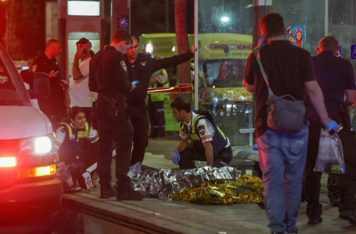 Secours et forces de sécurité israéliens se pressent autour d'un corps sans vie sur le lieu d'une attaque au couteau à Jérusalem, le 30 août 2023