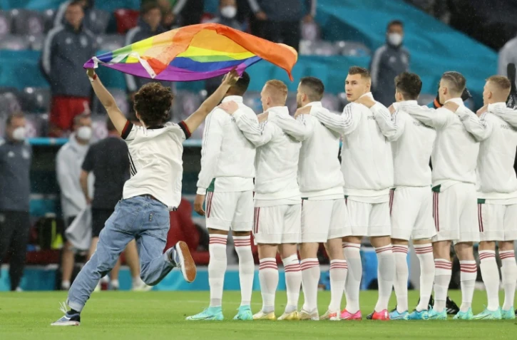 Une personne brandissant  un grand drapeau arc-en-ciel pendant l'hymne hongrois avant le match de l'Euro Allemagne-Hongrie le 23 juin 2021 à Munich
