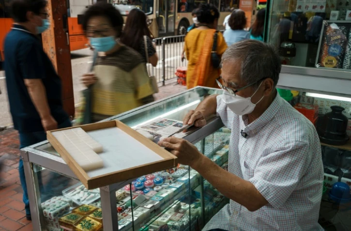 L'artisan Cheung Shun-king grave des caractères chinois sur des tuiles de mah-jong dans son échoppe du quartier de Yau Tsim Mong, le 6 juillet 2022 à Hong Kong