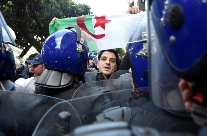 Un manifestant algérien fait face à la police antiémeute lors d'un rassemblement contre un 5e mandat du président Abdelaziz Bouteflika, à Alger le 24 février 2019
