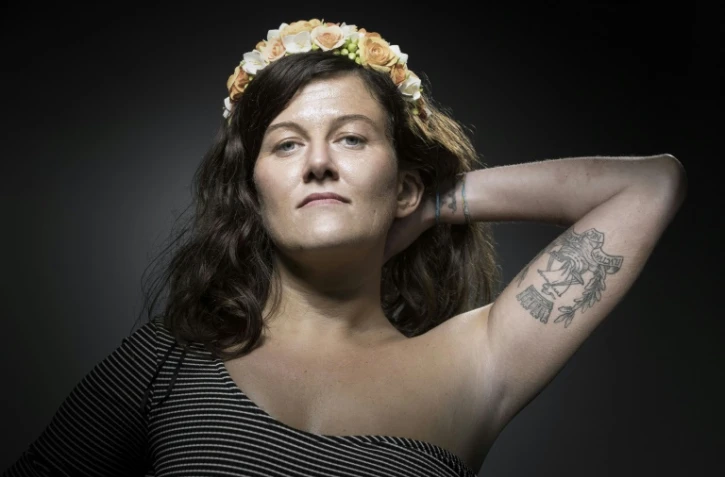 Alexandra D., qui prétendait avoir été blessée au bar du Carillon le 13 novembre 2015, montre son tatouage - la devise de Paris Fluctuat nec mergitur - lors d'une séance photo à Paris, le 26 juillet 2017