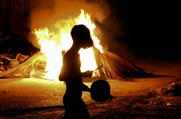 Un habitant tape sur une casserole devant un feu allumé lors d'une protestation contre les coupures de courant et les pénuries d'énergie à La Havane, le 14 mai 2026 à Cuba