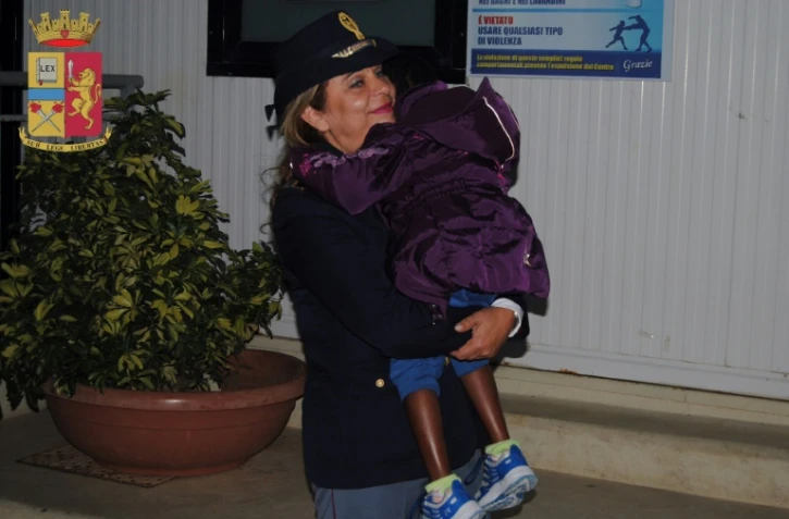 Oumoh, petite Ivoirienne de 4 ans, dans les bras de l'inspectrice Maria Volpe, chef du service des mineurs à la préfecture de police, le 5 novembre 2016 à  Agrigente en Italie