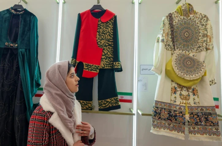 Une Iranienne regarde les créations présentées lors de l'exposition ayant lieu dans le cadre du festival national de la mode à Téhéran, et les vêtements conçus par de jeunes designers iraniens, le 21 janvier 2024