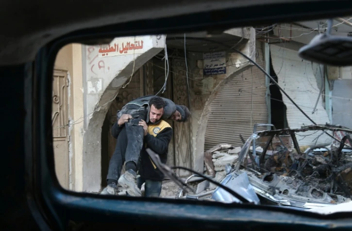 Un membre des Casques blancs syriens transporte un blessé après un bombardement du régime sur la ville de Hammouriyé, le 7 mars 2018 dans la Ghouta orientale