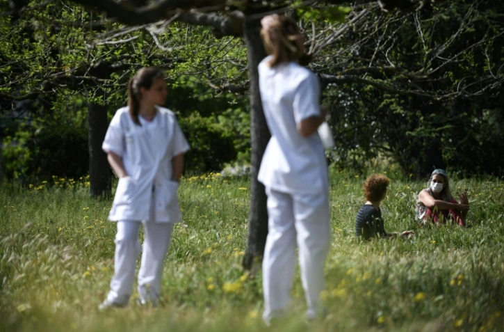 Des infirmières (dont une assise, avec le masque) et une patiente dans le jardin de l'hôpital psychiatrique marseillais de Valvert, le 16 avril 2020
