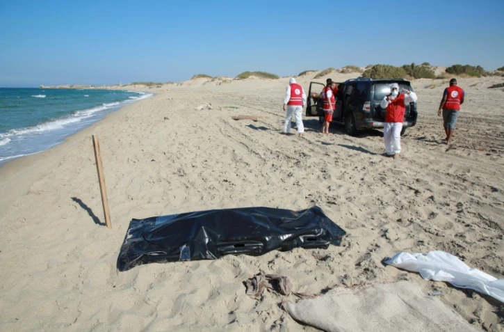 Des membres du Croissant Rouge cherchent le 26 juillet 2019 sur une plage de Khoms (Libye) les corps de migrants à bord d'une embarcation ayant fait naufrage