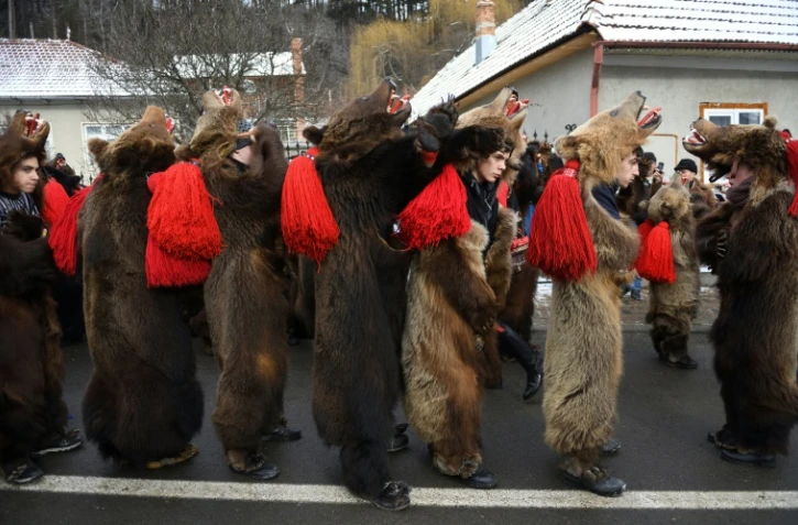Des roumains vêtus de peaux d'ours dansent dans les rues de Comanesti, le 30 décembre 2016 lors d'un défilé pour chasser les mauvais esprits de l'année écoulée