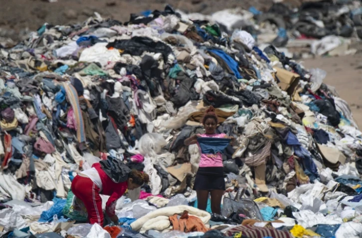 Des personnes cherchent des vêtements usagés dans une décharge sauvage à Alto Hospicio, au Chili, le 26 septembre 2021