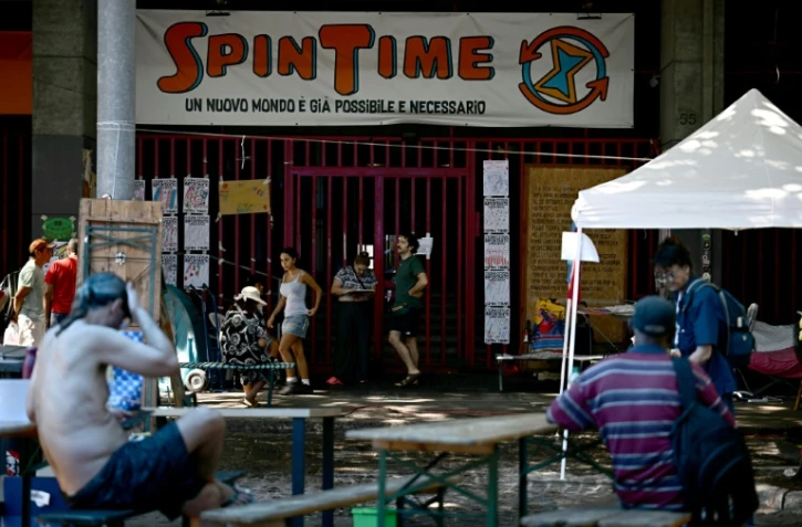 Des personnes récemment expulsées d'un centre social à Rome sont installées devant ses grilles fermées, le 11 août 2026