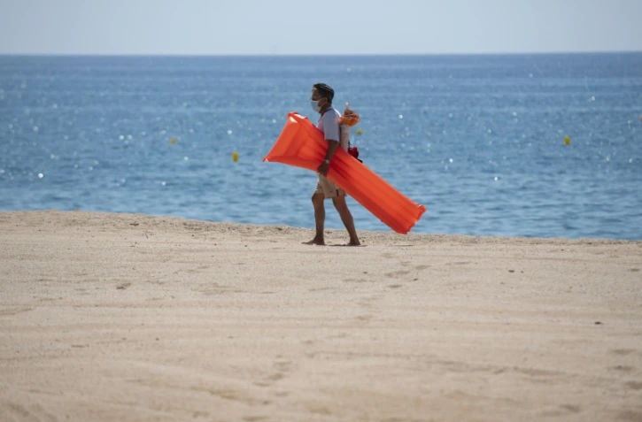 Un vacancier porte un masque de protection sur la plage de Lloret de Mar, le 22 juin 2020 en Espagne