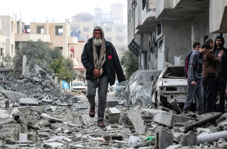 Un Palestinien marche au milieu des décombres d'une maison détruite par une frappe aérienne israélienne à Deir al-Balah, dans la bande de Gaza, le 13 mars 2024