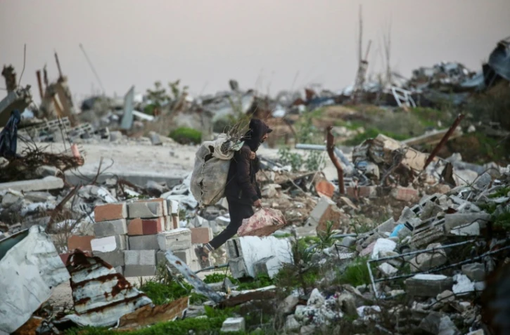 Un Palestinien transporte du bois à brûler dans les ruines du camp de réfugiés de Nousseirat, dans le centre de la bande de Gaza, le 31 décembre 2025
