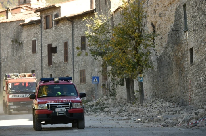 Des pompiers le 30 octobre 2016 dans une rue endommagée de Norcia après un puissant séisme