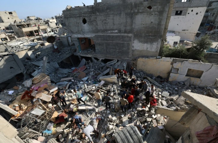 Des Palestiniens recherchent des survivants dans les décombres d'un bâtiment touché par une frappe israélienne à Bureij, dans le centre de la bande de Gaza, le 2 mai 2025
