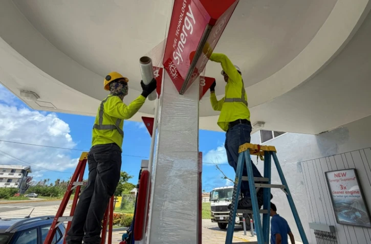 Des ouvriers consolident les panneaux d'une station service avant l'arrivée d'un "super typhon", le 4 juillet 2026 à Saipan, dans les Iles Mariannes du Nord