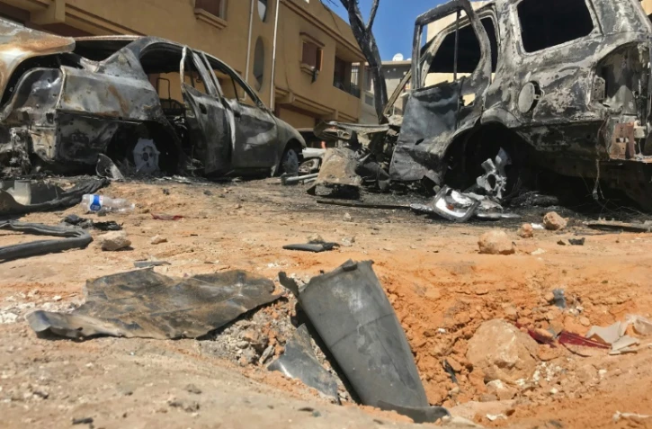 Les restes d'une roquette et des véhicules carbonisés le 17 avril 2019 dans un quartrier de Tripoli visé par des tirs la veille.