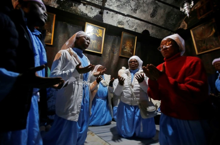 Des pèlerins chéritiens prient dans la grotte de la basilique de la Nativité, à Bethléem, en Cisjordanie occupée, le 24 décembre 2019
