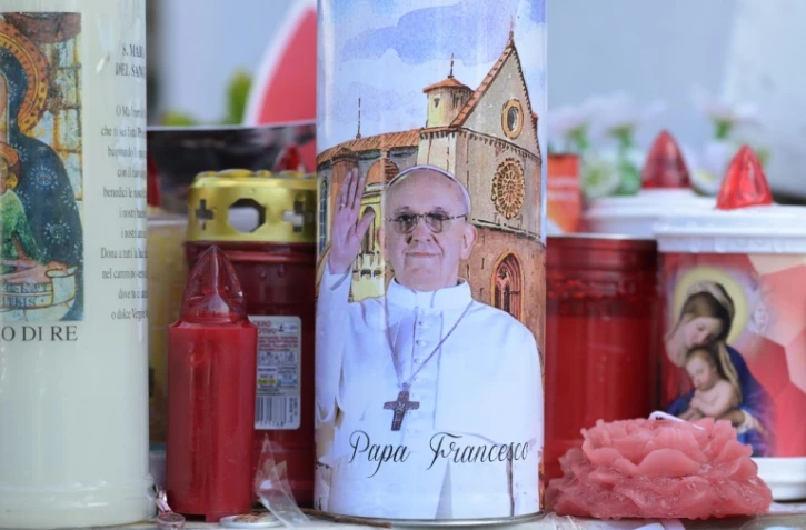 Des bougies déposées au pied de la statue de Jean-Paul II devant l'hôpital Gemelli à Rome où est hospitalisé le pape François, le 2 mars 2025