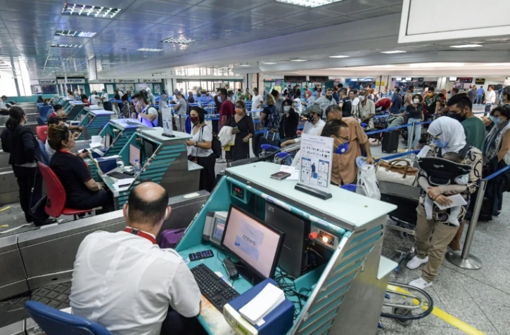 Des voyageurs masqués font la queue aux comptoirs d'enregistrement, le 27 juin 2020 à l'aéroport de Tunis
