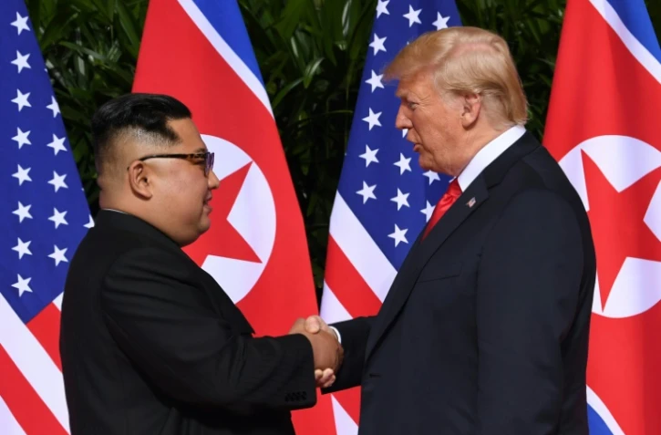Le leader nord-coréen Kim Jong Un (g) et le président américain Donald Trump se serrent la main, avant le début du sommet, à l'hôtel Capella, le 12 juin 2018 à Singapour