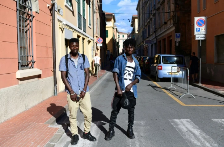 Blessed et Godwin, migrants du Nigeria, posent le 14 juin 2018 dans une rue de Vintimille, dans le nord de l'Italie, à proximité de la frontière avec la France