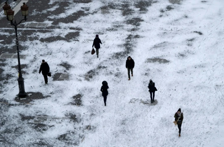 Des piétons marchent sur la neige, place de la Bourse à Paris le 1er mars 2018