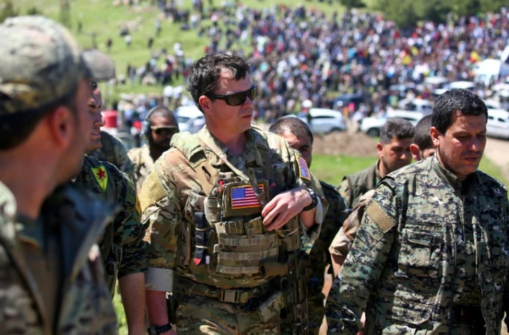 Un officier américain, de la coalition dirigée par les États-Unis, parle avec des combattants des unités de protection du peuple kurde (YPG) au nord-est de la ville kurde syrienne de Derik, connue sous le nom d'al-Malikiyah, le 25 avril, 2017