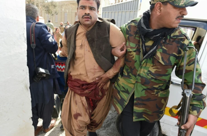 Un membre des forces de sécurité pakistanaise secourt un blessé après une attaque suicide conduite dans une église à Quetta, le 17 décembre 2017