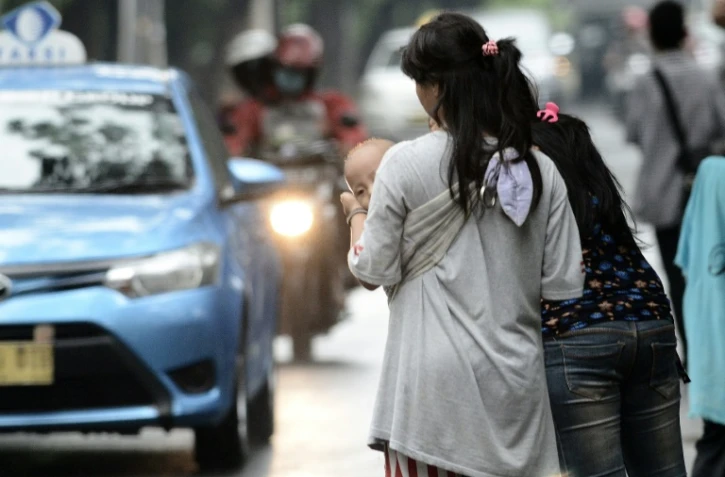 Une femme portant un enfant destiné à faire du co-voiturage à Jakarta, le 31 mars 2016