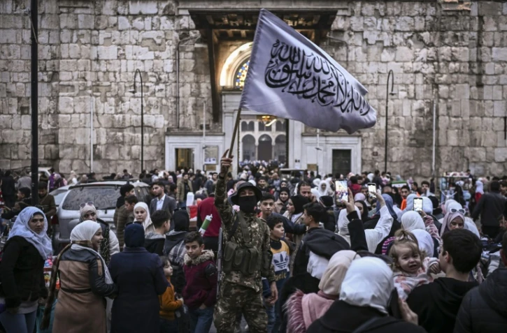 Un combattant rebelle brandit un drapeau islamique au souk Hamidiyeh, dans le Vieux Damas, le 11 décembre 2024
